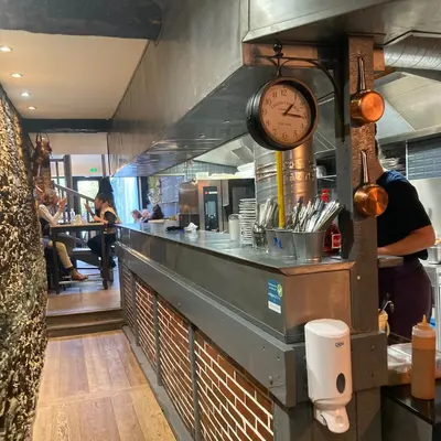 Comptoir de Mamilig ouvert sur la cuisine, horloge de gare et casseroles en cuivre