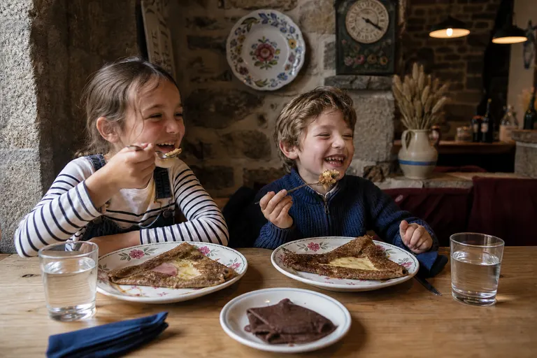 Deux enfants qui mangent leur galette à la crêperie