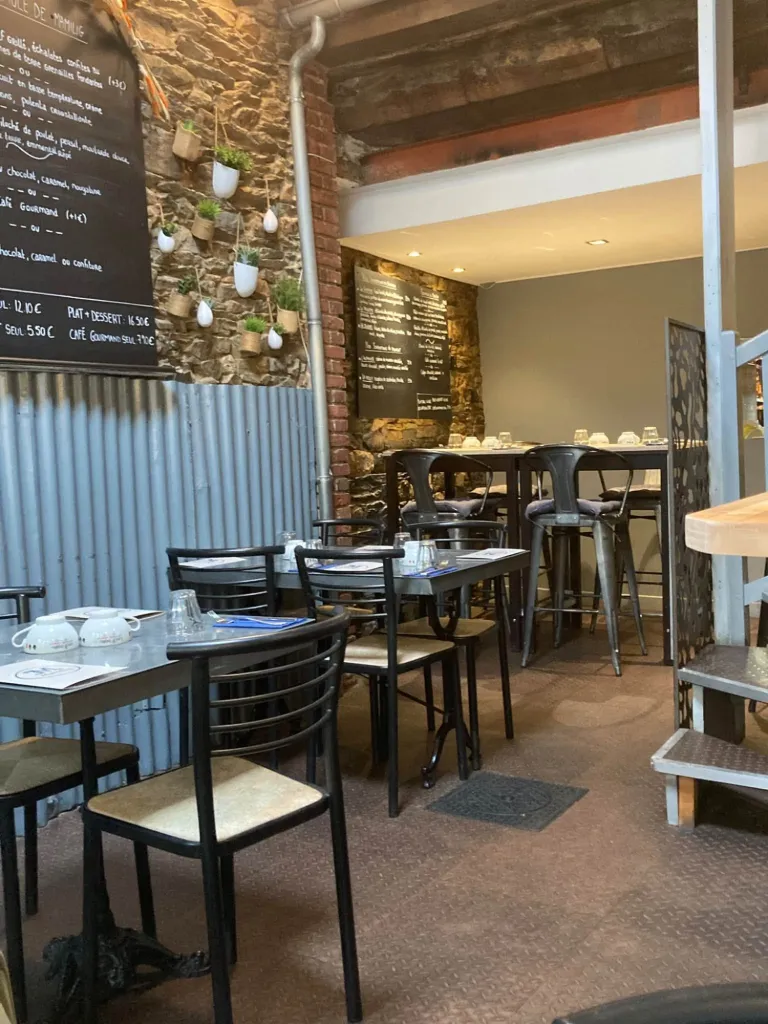 La salle de Mamilig, crêperie-bistrot de Châteaugiron près de Rennes : tables bistrot, mur de pierre et ardoise des suggestions